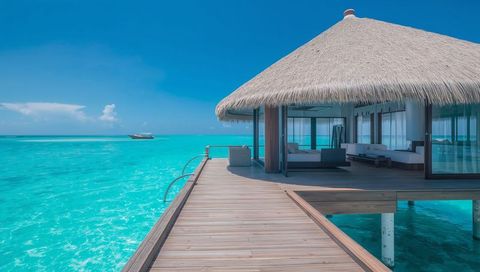Luxury overwater villa retreat with thatched roof, turquoise lagoon pier and private deck