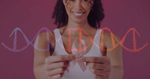 Smiling woman holding pink breast cancer ribbon with dna helix overlay for awareness and hope