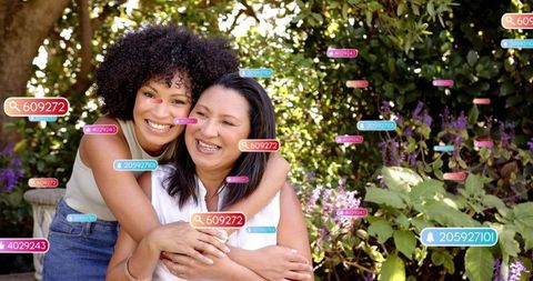 Adult daughter hugging seated mother in sunlit garden with digital tags, family connection