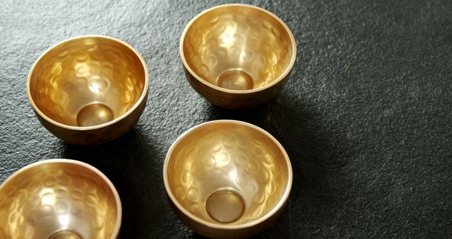 Golden hammered metal bowls on dark textured surface - Download Free Stock Images Pikwizard.com