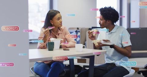 Coworkers chatting and eating lunch in modern office breakroom with digital social tags