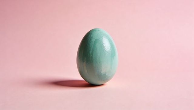 Seafoam painted egg standing on pastel pink backdrop with glossy brush stroke texture