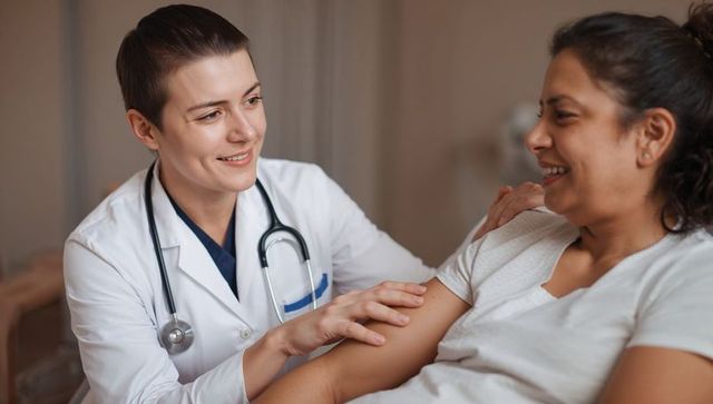 Clinician offering gentle bedside care and reassurance during patient consultation