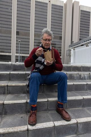 Senior man eating takeout on urban steps during overcast day