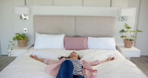 Woman Relaxing on Bed in Modern Cozy Bedroom