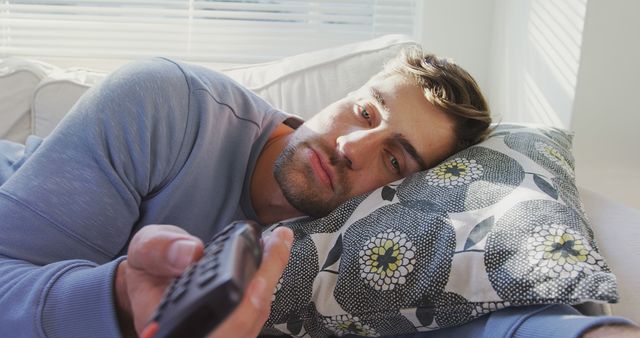 Relaxed Young Man Watching TV While Lying on Sofa - Download Free Stock Images Pikwizard.com