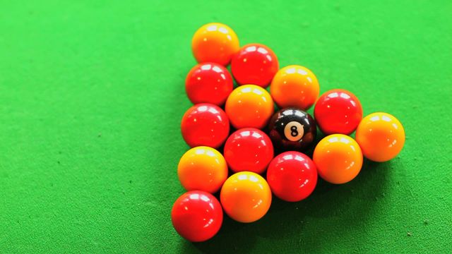 This image captures a close-up of a billiards break with vibrant pool balls arranged artistically on a green table. The numbers and colorful contrasts create a lively composition, making it ideal for promoting sporting events, casual recreational settings, or games room decoration. It can appeal to enthusiasts of billiards and teaching techniques to beginning learners.