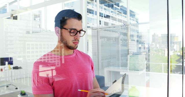 Focused Young Man Taking Notes in Modern Office With City View - Download Free Stock Images Pikwizard.com