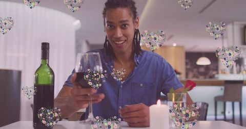 man at restaurant table enjoying a glass of wine. heart icons overlay suggest digital interaction, such as a video call. ideal for social media promotions, dating apps, or communication technology marketing emphasizing connection and enjoyment.