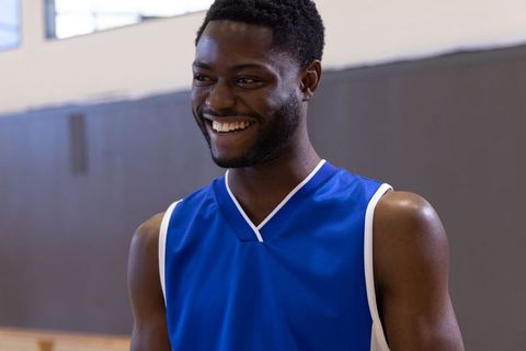 Smiling african american basketball player in blue jersey on indoor court