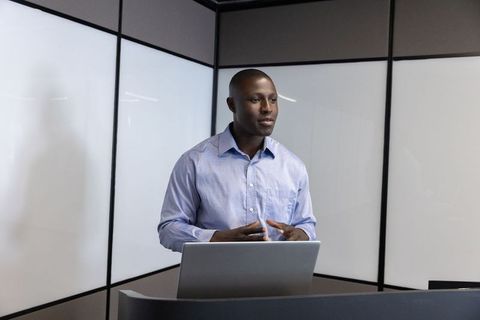 Confident Speaker Presenting in Modern Office with Laptop