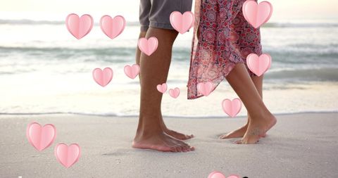 feet of a diverse couple lightly touching on a sandy beach, surrounded by floating hearts. the sense of romance is heightened by their connected stance, ideal for themes of love and valentine's day. perfect for use in romantic imagery, advertising romantic getaways, or any content celebrating love and heartfelt connections.