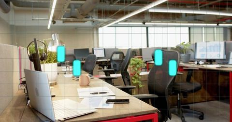 Bright modern open-plan coworking desk featuring laptop, smartphone, mug and plants