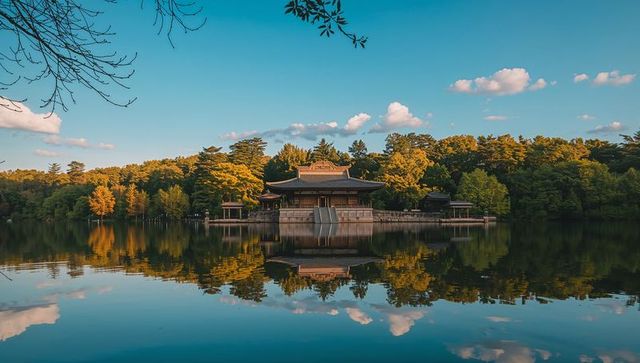 Sunlit traditional east asian lakeside pavilion reflecting in calm mirror water