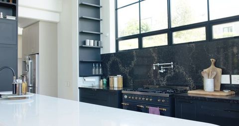 Showcasing large white quartz island anchoring modern kitchen with black range and matte faucet