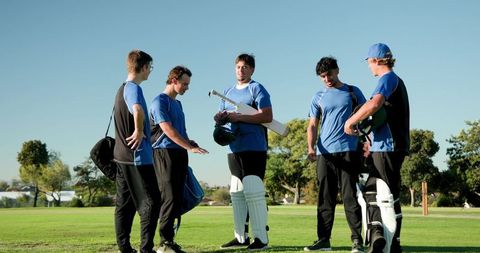 Youth cricket team discussing field strategy and walking off pitch showing camaraderie
