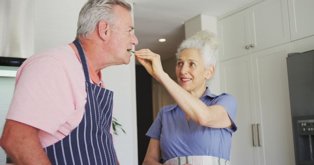 Happy caucasian senior couple wearing aprons cooking together in kitchen. active and healthy retirement lifestyle at home.