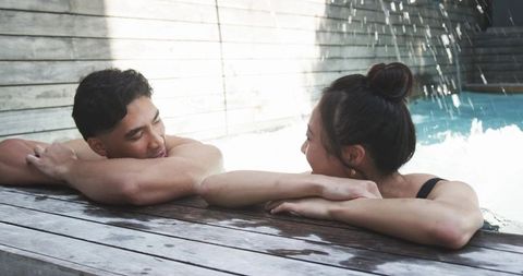 Sunlit couple relaxing at private pool deck with fountain, intimate resort lifestyle