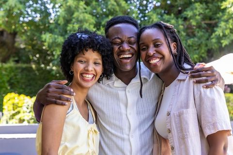 Laughing african american friends embracing in sunlit garden, casual summer joy portrait