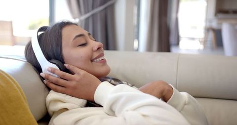 Woman Enjoying Music with Headphones Lying on Couch