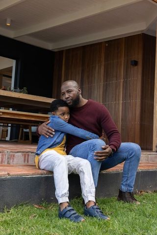 African american father embracing son on porch, showing comfort, connection and calm