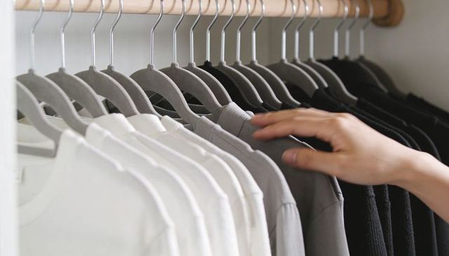 Hand selecting shirt from minimal monochrome closet on grey velvet hangers
