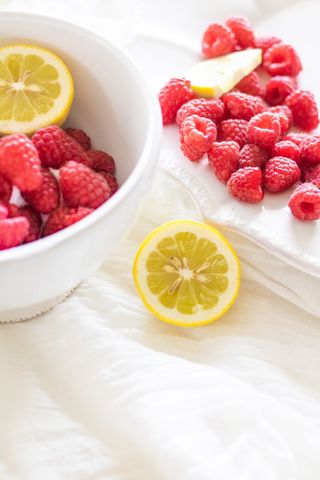 Bright raspberries and lemon slices resting on soft white linens