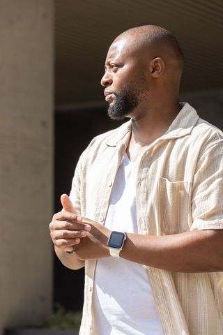Sunlit urban portrait of man wearing smartwatch and casual beige shirt