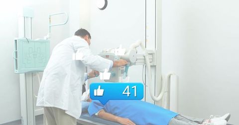 Doctor adjusting x-ray machine over patient in blue gown during radiology exam