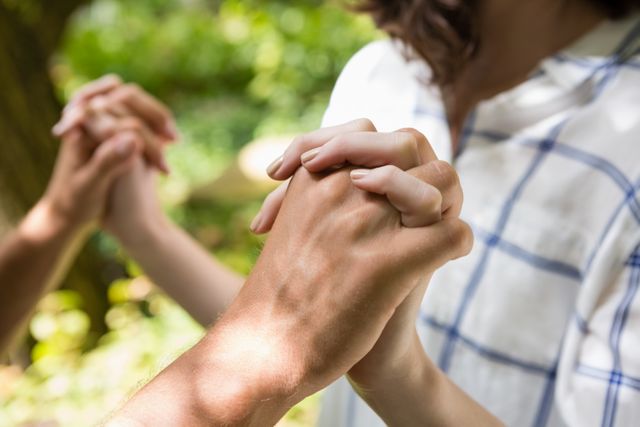 This image captures a close-up view of a couple holding hands in a garden, symbolizing love, connection, and intimacy. Ideal for use in relationship blogs, romantic greeting cards, wedding invitations, or any content related to love and togetherness.