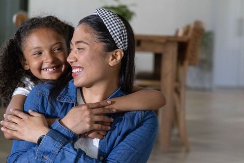 African american mother hugging daughter and smiling together at home warm family bond