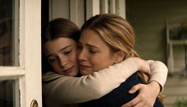 Mother embracing daughter on front porch comforting hug at doorway, emotional family scene