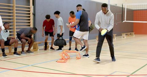 African american men preparing for volleyball conditioning with hurdles and cones