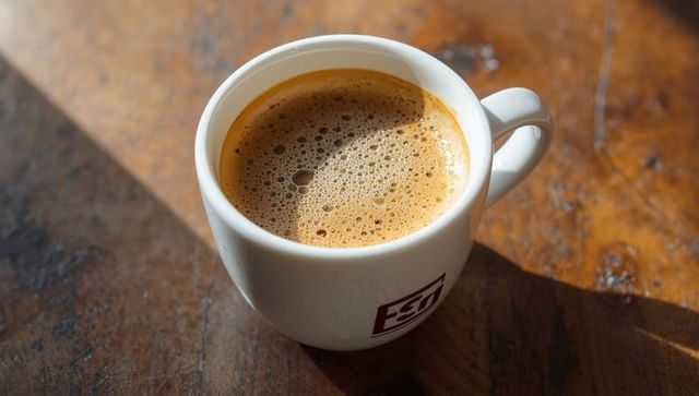 Warm Ceramic Coffee Mug with Frothy Brew on Wooden Table