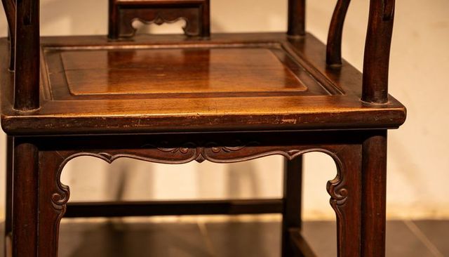 Antique hardwood chair showing carved apron, scuffed seat corner and warm patina