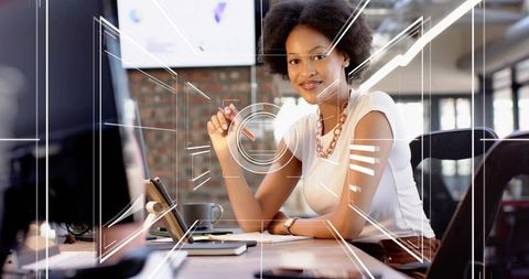 Young professional woman working at modern desk with digital hud overlays