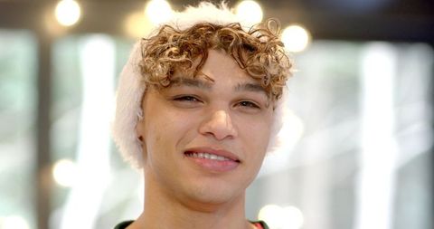 Smiling Young Man in Cozy Knit Hat with Soft Blurry Lights