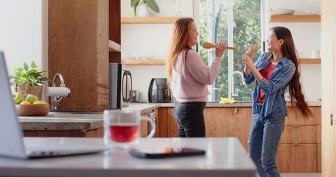 Joyful Mother and Daughter Singing in Kitchen