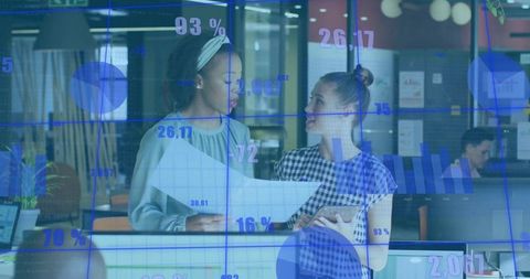 Two professional women collaborating on data analytics in modern office