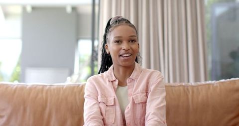 Young Woman with Braided Hair Relaxing on Couch in Bright Living Room