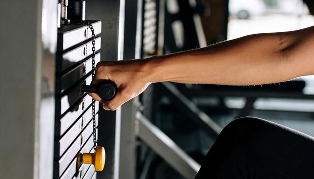 Gripping weight stack selector pin during cable machine workout, forearm detail