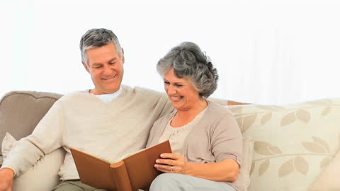Senior Couple Enjoying Moments with Photo Album on Couch