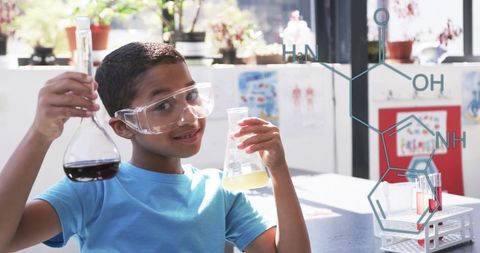 Smiling boy holding beakers in school science class