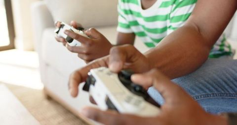 Playing couch co-op with white controllers, closeup hands on joysticks