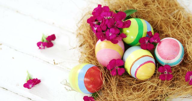 Colorful Easter eggs nestled in a nest with vibrant pink flowers, with copy space. These festive decorations symbolize rebirth and are commonly used in celebrations of the Easter holiday.