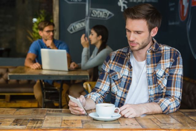 Man using mobile phone while having coffee in cafÃ©