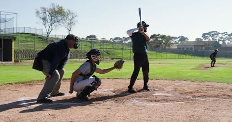 Amateur baseball batter catcher and umpire ready at home plate on sunny local game field