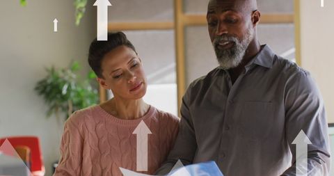 Colleagues discussing documents with growth arrows overlay