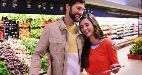 Happy couple shopping in organic produce section of supermarket
