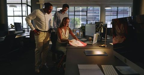 Diverse Team Collaborating on Project in Modern Office at Night